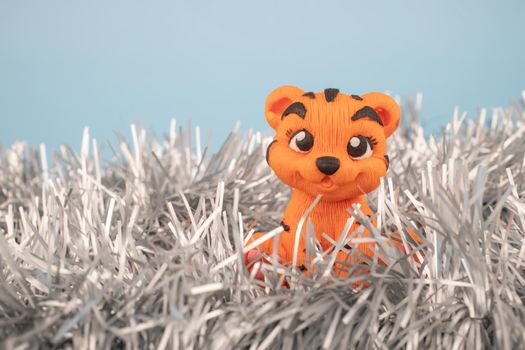 Orange handmade tiger figurine on a blue background with a notepad for notes. The year 2022 is the new year of the tiger according to the Eastern calendar.