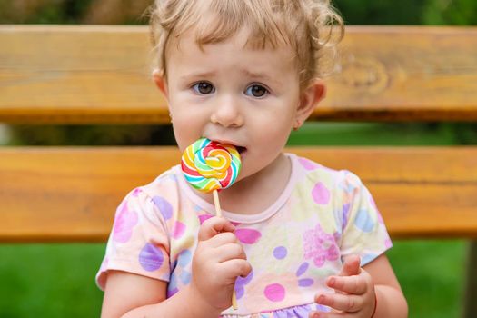 Baby eats a lollipop in the park. Selective focus. Child.