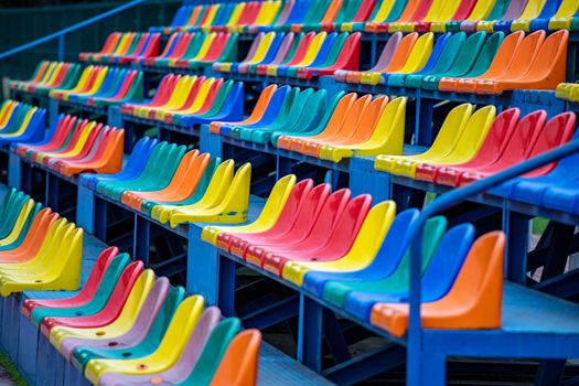 A row of colorful chairs on the stadium stand. Colorful seats for the public