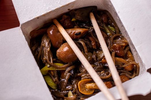 chinese food buckwheat noodles with mushrooms close-up. Open paper box