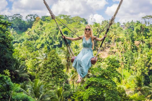 Young woman swinging in the jungle rainforest of Bali island, Indonesia. Swing in the tropics. Swings - trend of Bali.