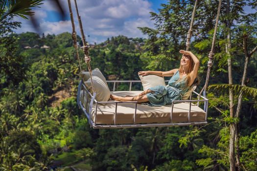 Young woman swinging in the jungle rainforest of Bali island, Indonesia. Swing in the tropics. Swings - trend of Bali.