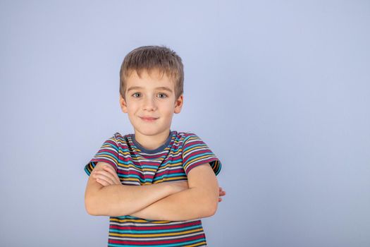 A little boy dressed in a multicolored striped T-shirt. Portrait of a beautiful teenage boy of early age. The pose of a happy smile.