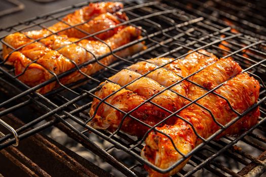 Traditional baked barbecue chicken on a charcoal grill. Grilling and smoking chicken outdoors in nature on a family picnic.