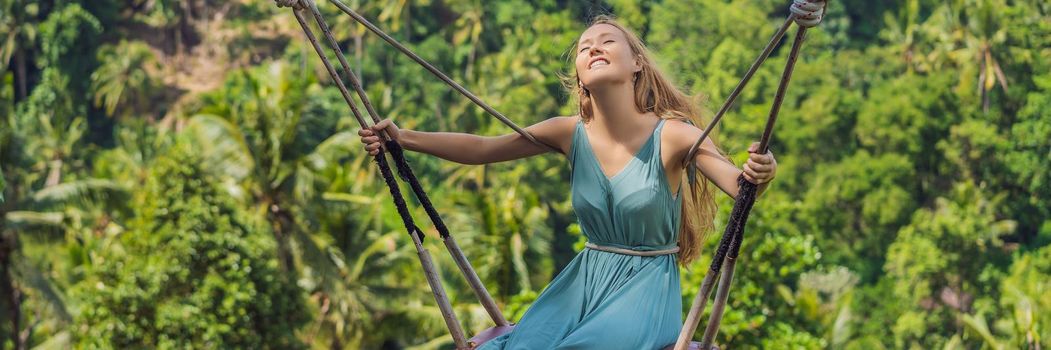 Young woman swinging in the jungle rainforest of Bali island, Indonesia. Swing in the tropics. Swings - trend of Bali. BANNER, LONG FORMAT