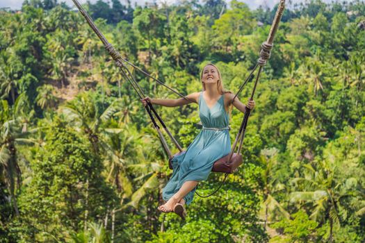 Young woman swinging in the jungle rainforest of Bali island, Indonesia. Swing in the tropics. Swings - trend of Bali.