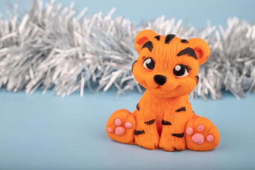 A hand-sculpted orange tiger figurine on a blue background with a notepad for notes. The year 2022 is the year of the tiger according to the Eastern calendar.