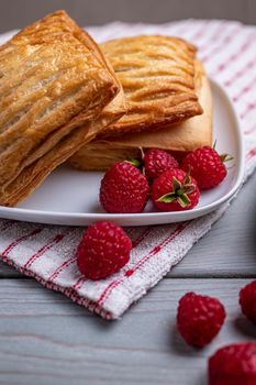 Delicious fresh croissants and sweet raspberry puffs on a wooden table. Selected focus.