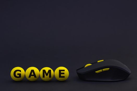 a black wireless computer mouse with yellow buttons on a background of a black grid textured in the form of hexagons and yellow soft balls with the inscription game