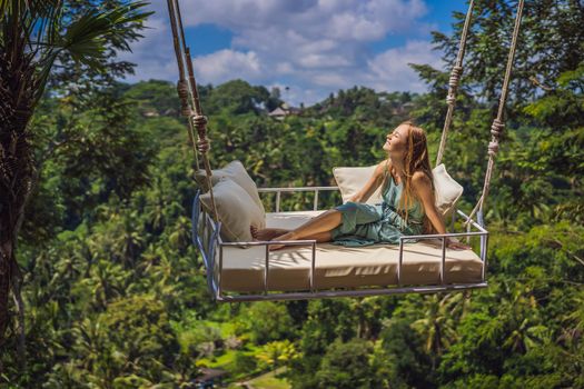 Young woman swinging in the jungle rainforest of Bali island, Indonesia. Swing in the tropics. Swings - trend of Bali.