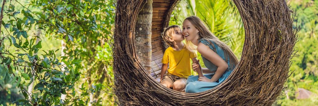 BANNER, LONG FORMAT Bali trend, straw nests everywhere. Happy family enjoying their travel around Bali island, Indonesia. Making a stop on a beautiful hill. Photo in a straw nest, natural environment. Lifestyle. Traveling with kids concept. What to do with children. Child friendly place.