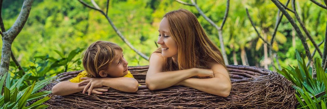 BANNER, LONG FORMAT Bali trend, straw nests everywhere. Happy family enjoying their travel around Bali island, Indonesia. Making a stop on a beautiful hill. Photo in a straw nest, natural environment. Lifestyle. Traveling with kids concept. What to do with children. Child friendly place.