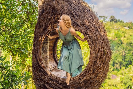 Bali trend, straw nests everywhere. Young tourist enjoying her travel around Bali island, Indonesia. Making a stop on a beautiful hill. Photo in a straw nest, natural environment. Lifestyle.