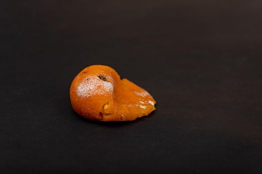 Crushed rotten and moldy tangerine on a black background. Damaged Tangerine. Bad Christmas concept.