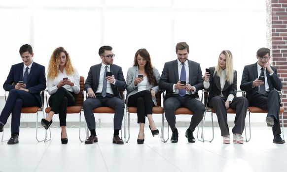 employees with smartphones sitting in the lobby. people and technology