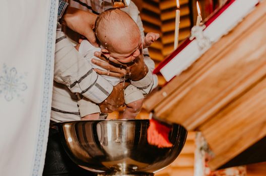 rite of sacrament of epiphany baby in church. priest washes child with Sacred water.