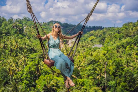 Young woman swinging in the jungle rainforest of Bali island, Indonesia. Swing in the tropics. Swings - trend of Bali.