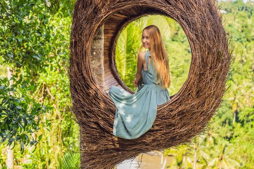 Bali trend, straw nests everywhere. Young tourist enjoying her travel around Bali island, Indonesia. Making a stop on a beautiful hill. Photo in a straw nest, natural environment. Lifestyle.