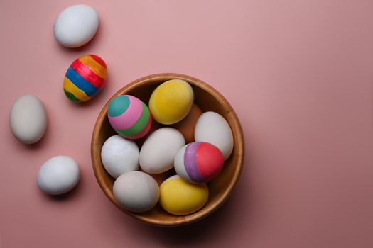 Easter basket filled with painted Easter Eggs over pink background.