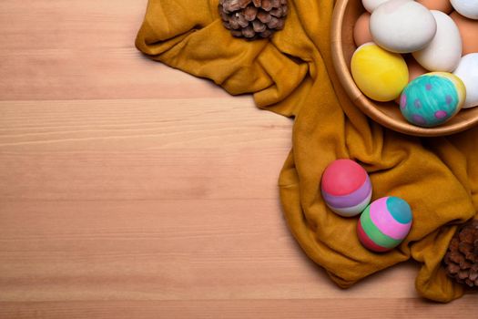 Above view Easter basket filled with painted Easter eggs over wooden background.