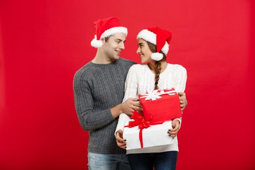 Christmas Concept - handsome young boyfriend in Christmas sweater surprise his girlfriend with gifts.