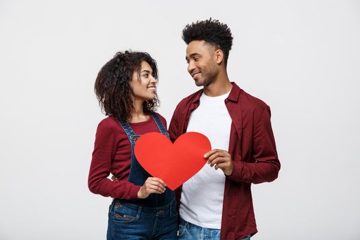 Young happy African American couple in love holding red paper heart