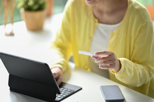 Cropped shot of female hands making online payment via computer tablet. Online shopping, e-commerce, banking concept.