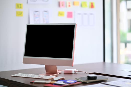 Modern workplace with computer, stationery and paperworks on wooden table.