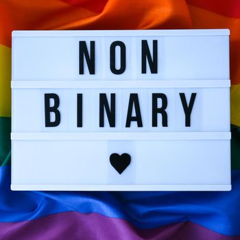 Rainbow flag with lightbox and text NON BINARY. Rainbow lgbtq flag made from silk material. Symbol of LGBTQ pride month. Equal rights. Peace and freedom. Support LGBTQ community