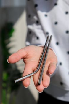 Woman holding Reusable Metal Straw. Female Hand on reusable collapsible drinking straw. Eco lifestyle and zero waste concept. Plastic free. Stainless metal straws