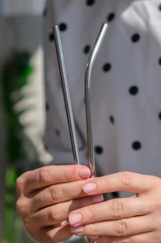 Woman holding Reusable Metal Straw. Female Hand on reusable collapsible drinking straw. Eco lifestyle and zero waste concept. Plastic free. Stainless metal straws