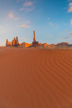 Totem pole and sand dunes  in Monument Valley, Arizona USA at sunset