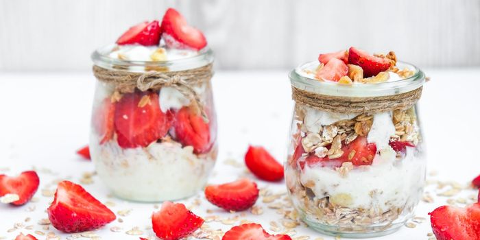 Healthy breakfast. Oatmeal Granola with greek yogurt and nuts strawberry muesli in jars on light background. Vegan, vegetarian and weight loss diet concept. Detox menu. Healthy eating food