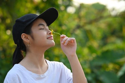 Adorable little girl with closed eyes smelling flower in her hand. Ecology, Earth day, Hobbies, Leisure, Home gardening concept.