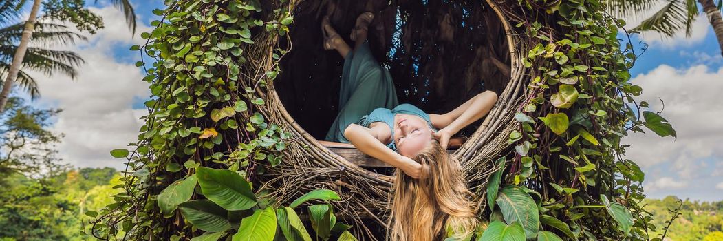 BANNER, LONG FORMAT Bali trend, straw nests everywhere. Young tourist enjoying her travel around Bali island, Indonesia. Making a stop on a beautiful hill. Photo in a straw nest, natural environment. Lifestyle.