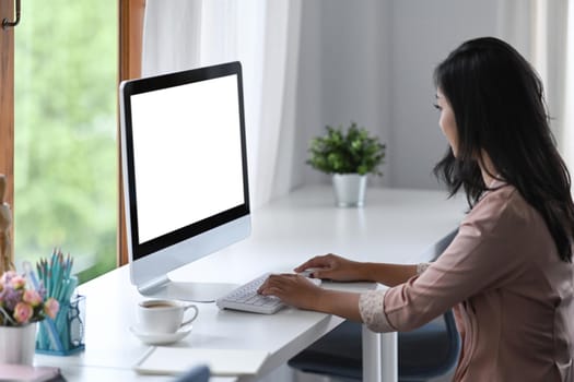 Side view young female entrepreneur using computer at office desk.
