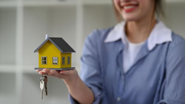 Real estate agent with house model and keys. New house, insurance and real estate concept.