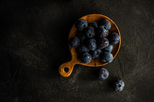 Raw organic blueberry in wooden spoon - bowl on textured background