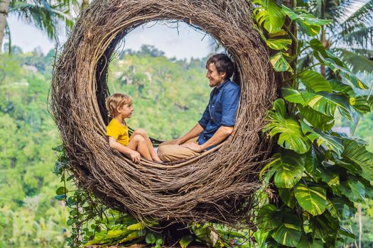 Bali trend, straw nests everywhere. Child friendly place. Happy family enjoying their travel around Bali island, Indonesia. Making a stop on a beautiful hill. Photo in a straw nest, natural environment. Lifestyle. Traveling with kids concept. What to do with children.