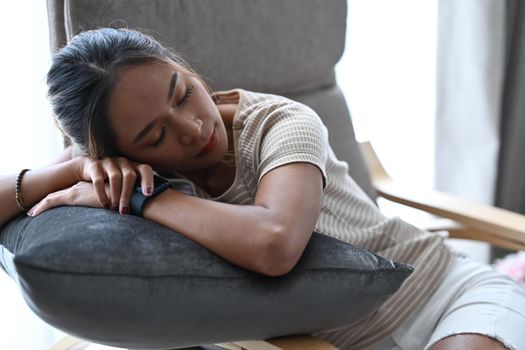 Millennial woman in casual clothes sleeping on comfortable armchair at home.