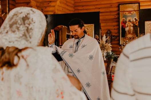 Letychiv, Ukraine - 10.15.2020: rite of sacrament of epiphany child baby in church. rite of sacrament of epiphany child baby in church. The priest blesses godparents and baptizes them.