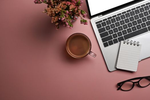 Flat lay, laptop computer, coffee cup, glasses and dry flowers on pink background. Feminine workspace.