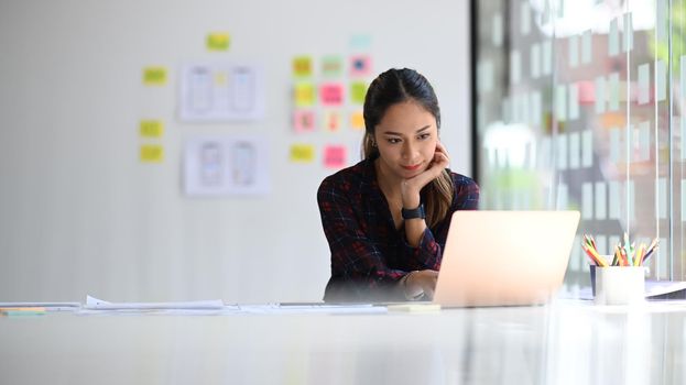 Concentrated female web developer working on mobile application software design project at modern workplace.