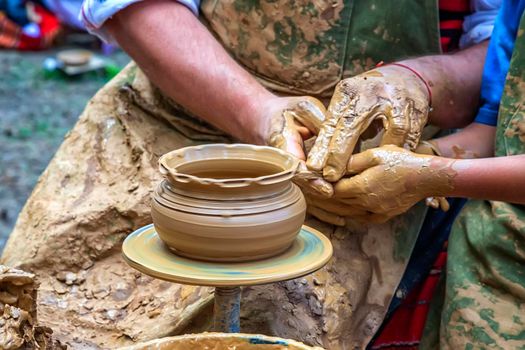 A master of pottery craftsmanship teaches a child who wants to learn how to sculpt a jug. Pottery master class.