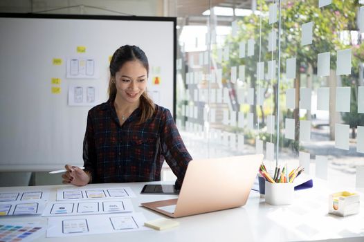 Attractive female designer working on mobile app development at modern workplace.