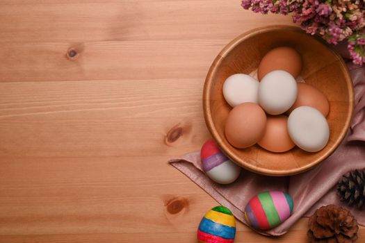 Painted Easter eggs with spring flowers on wooden background. Happy Easter concept.