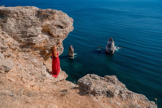 A woman in a red flying dress fluttering in the wind, against the backdrop of the sea