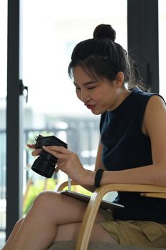 Female freelancer setting and checking picture previews on her camera.