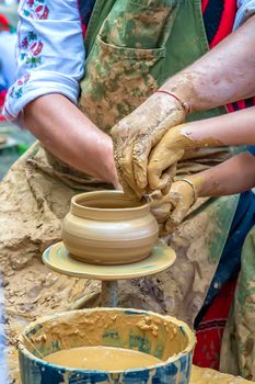 A master of pottery craftsmanship teaches a child who wants to learn how to sculpt a jug. Pottery master class.