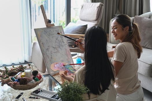 Back view of asian girl enjoy painting picture with her mother at home.